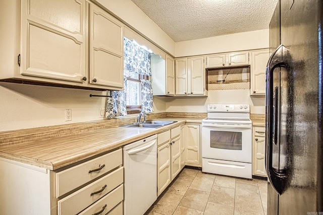 kitchen featuring sink, white appliances, a textured ceiling, and light tile patterned flooring