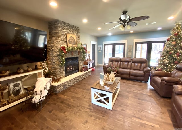 living room with french doors, a stone fireplace, ceiling fan, and wood-type flooring