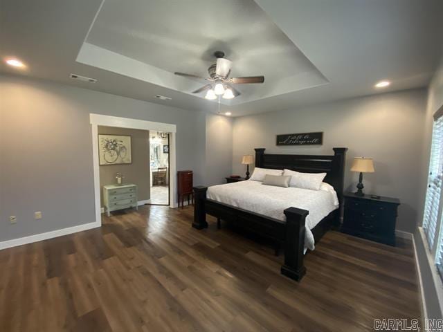 bedroom with a tray ceiling, ceiling fan, and dark wood-type flooring