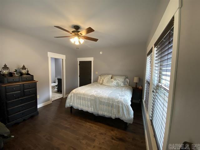 bedroom featuring connected bathroom, ceiling fan, and dark wood-type flooring