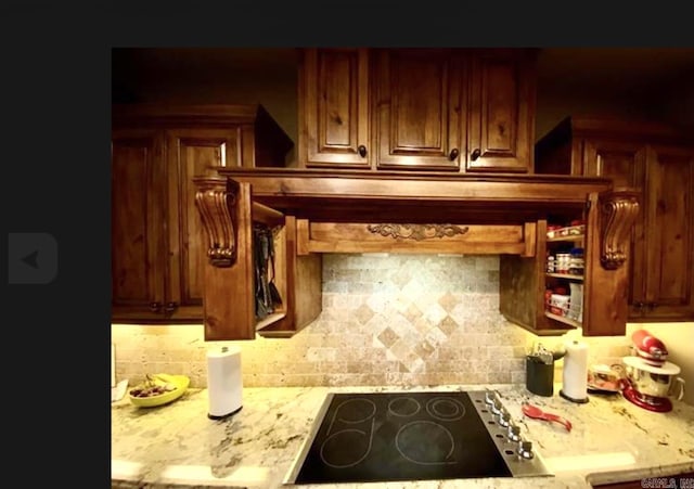 kitchen featuring light stone countertops, backsplash, and black electric cooktop