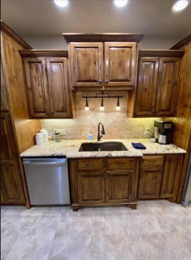 kitchen with backsplash, dishwasher, light stone countertops, and sink