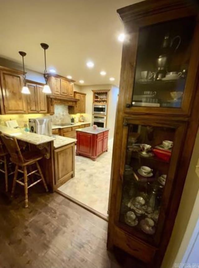 kitchen featuring kitchen peninsula, a kitchen breakfast bar, backsplash, and cooktop