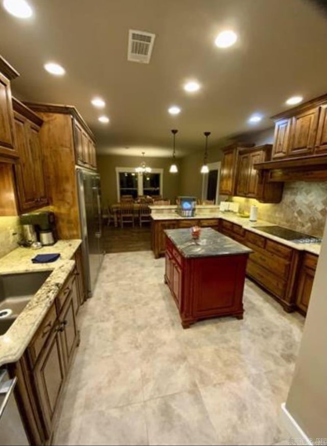 kitchen with a center island, black electric stovetop, stainless steel fridge, tasteful backsplash, and decorative light fixtures