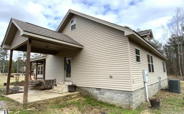 view of side of property with a patio and central AC