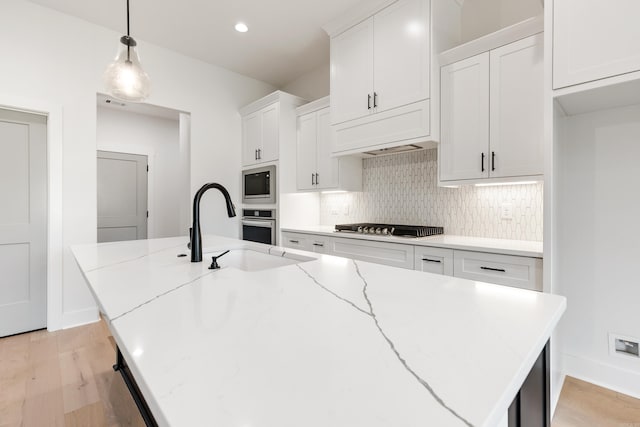 kitchen featuring white cabinetry, light stone countertops, stainless steel appliances, and hanging light fixtures