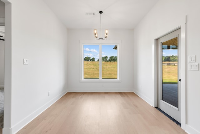 unfurnished dining area featuring a notable chandelier, light hardwood / wood-style floors, and a wealth of natural light