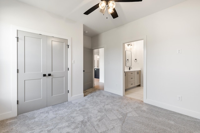 unfurnished bedroom featuring ceiling fan, ensuite bath, light carpet, and a closet