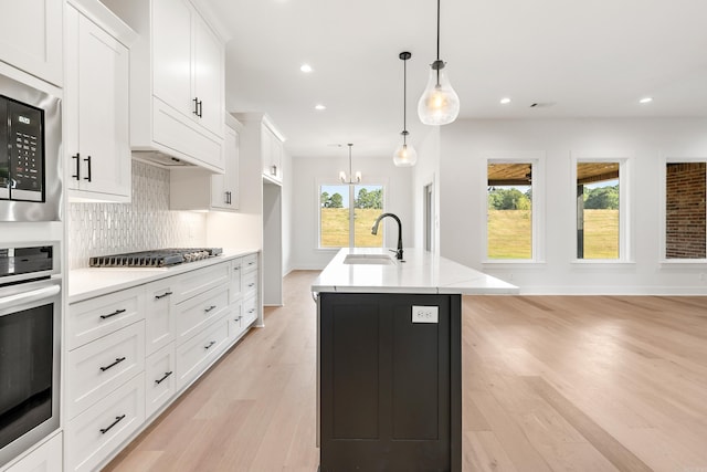 kitchen featuring a kitchen island with sink, sink, white cabinets, and appliances with stainless steel finishes