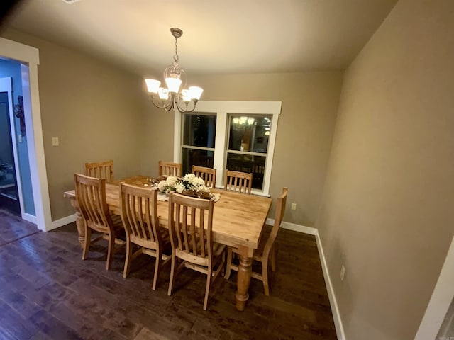 dining space with dark hardwood / wood-style flooring and an inviting chandelier