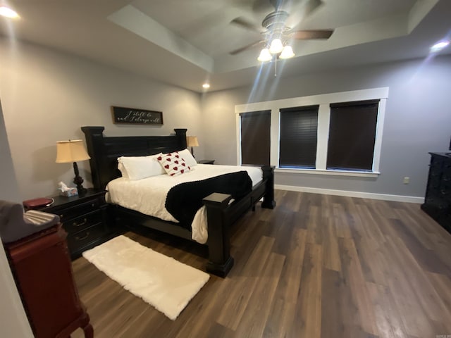 bedroom featuring dark hardwood / wood-style flooring, a raised ceiling, and ceiling fan