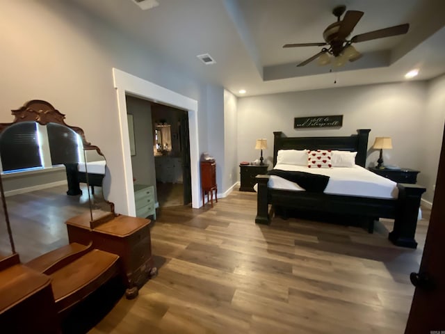 bedroom featuring a tray ceiling, ceiling fan, and wood-type flooring