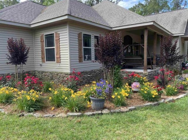 view of side of property featuring a lawn and covered porch