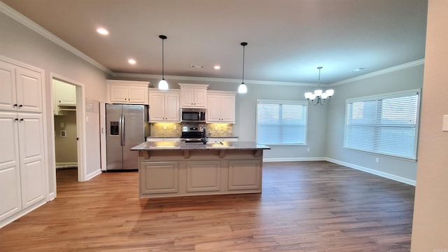 kitchen featuring appliances with stainless steel finishes, a kitchen island with sink, pendant lighting, light hardwood / wood-style floors, and white cabinetry