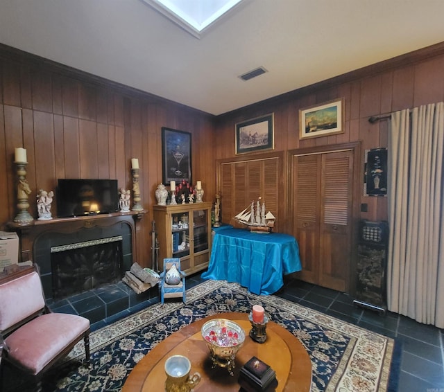 living room featuring a fireplace, wood walls, and dark tile patterned floors