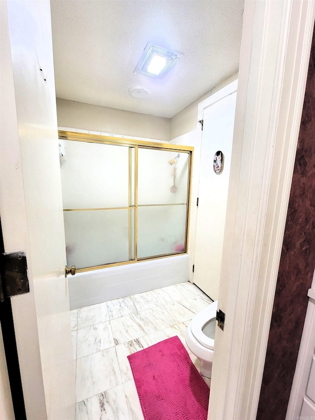 bathroom with bath / shower combo with glass door, a textured ceiling, and toilet