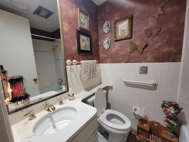 full bathroom with vanity, toilet, washtub / shower combination, and tile walls