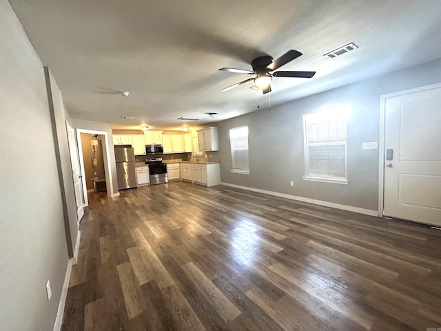 unfurnished living room featuring ceiling fan and dark wood-type flooring