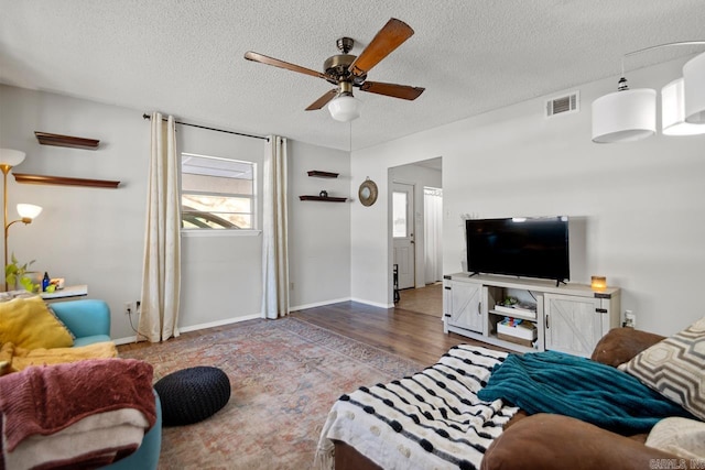 living room with a textured ceiling, hardwood / wood-style flooring, and ceiling fan