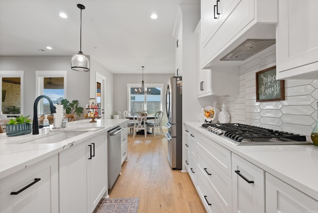 kitchen featuring white cabinetry, sink, hanging light fixtures, tasteful backsplash, and appliances with stainless steel finishes