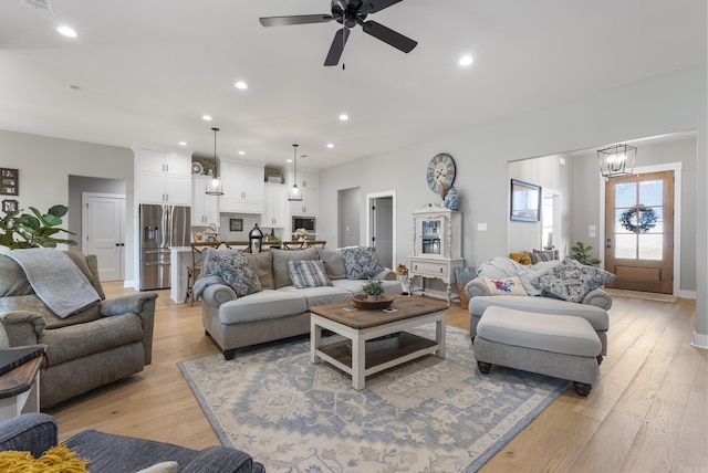 living room featuring light hardwood / wood-style flooring and ceiling fan with notable chandelier