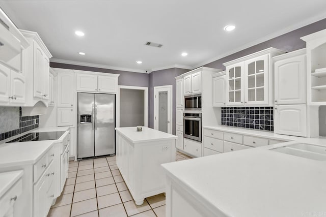 kitchen featuring appliances with stainless steel finishes, a center island, white cabinetry, and backsplash