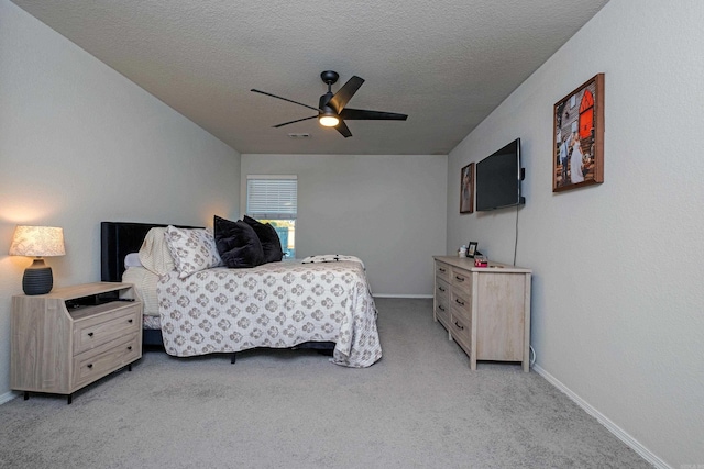 bedroom featuring ceiling fan, light colored carpet, and a textured ceiling