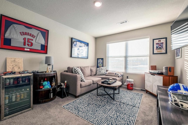 living room featuring carpet, a textured ceiling, and beverage cooler