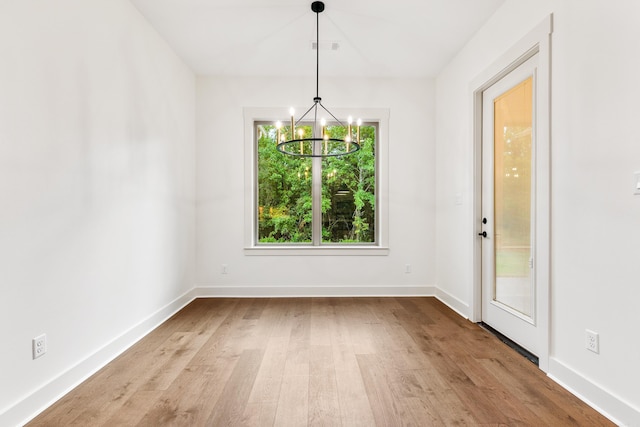 unfurnished dining area featuring light wood-type flooring and a notable chandelier