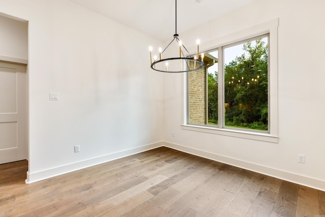 unfurnished dining area with a wealth of natural light, light hardwood / wood-style flooring, and a chandelier