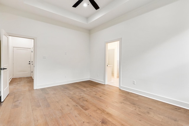 spare room featuring a raised ceiling, ceiling fan, and light hardwood / wood-style floors