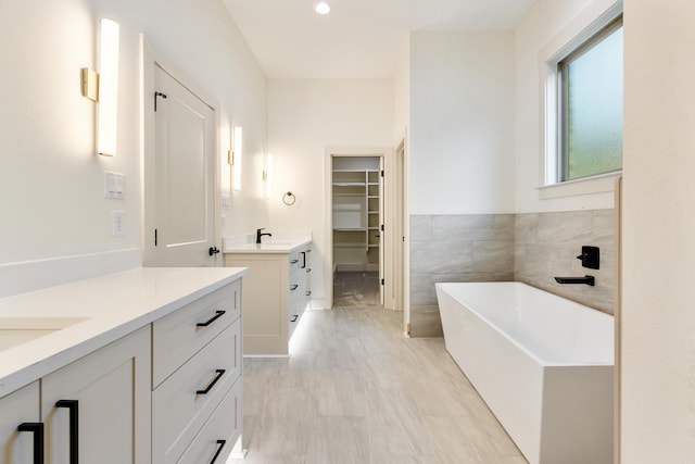 bathroom with a bathing tub, vanity, and tile walls