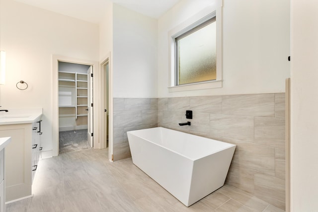 bathroom with vanity, a bathtub, and tile walls