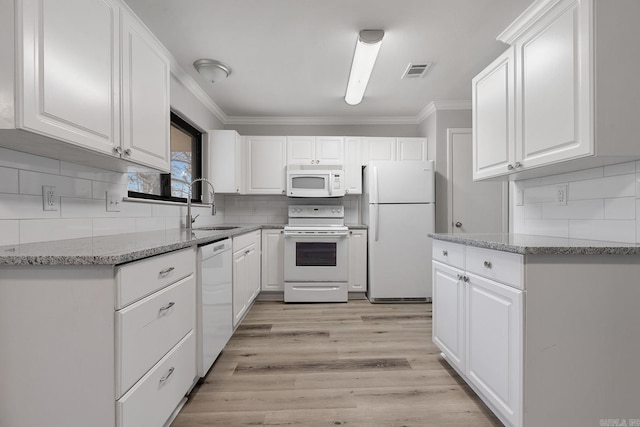 kitchen with light stone counters, sink, white cabinets, and white appliances