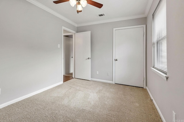 unfurnished bedroom featuring multiple windows, light colored carpet, ceiling fan, and ornamental molding