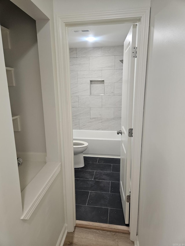 bathroom featuring tiled shower / bath combo and toilet