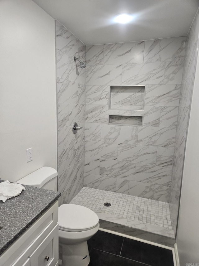 bathroom with tiled shower, vanity, and toilet