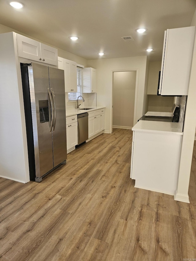 kitchen featuring light wood-type flooring, stainless steel appliances, white cabinetry, and sink