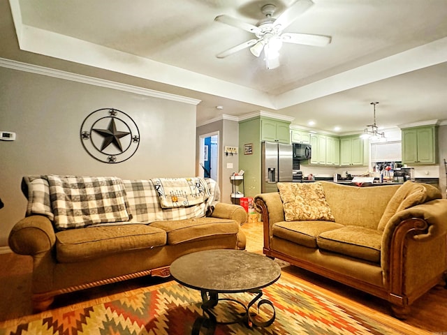 living room featuring a raised ceiling, ceiling fan, and ornamental molding