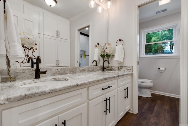 bathroom featuring wood-type flooring, vanity, ornamental molding, and toilet