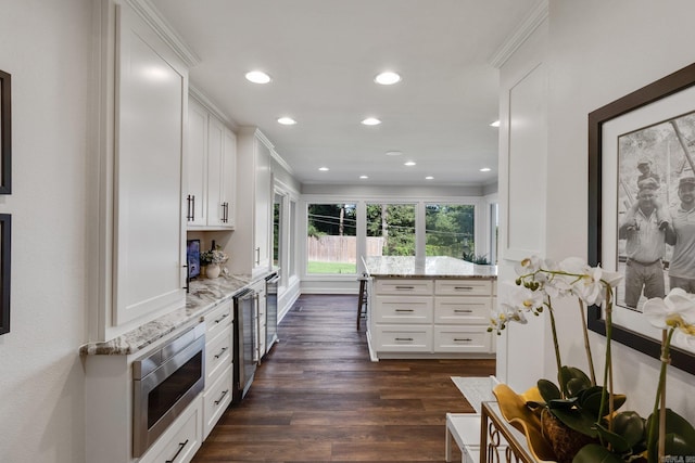 kitchen with light stone counters, white cabinetry, dark wood-type flooring, and stainless steel microwave