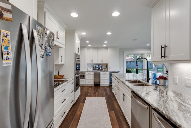 kitchen with white cabinets, appliances with stainless steel finishes, light stone counters, and sink