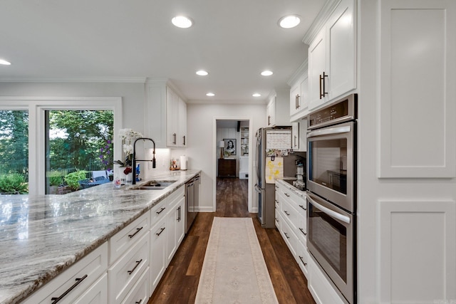 kitchen featuring white cabinets, appliances with stainless steel finishes, light stone countertops, and sink