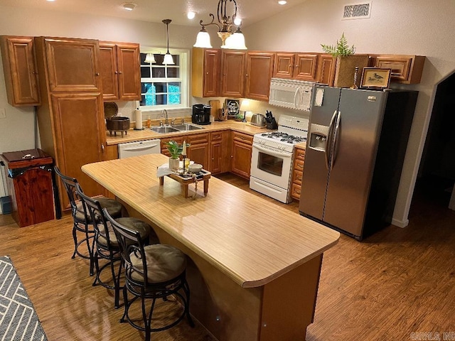 kitchen featuring hardwood / wood-style floors, sink, pendant lighting, and white appliances