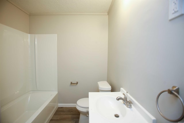 full bathroom with bathing tub / shower combination, sink, hardwood / wood-style flooring, toilet, and a textured ceiling