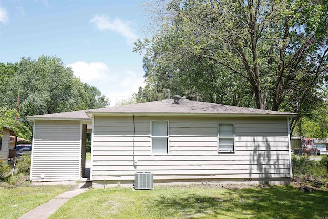 view of side of property featuring central AC unit and a lawn