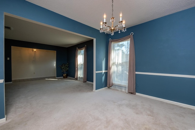 unfurnished room with carpet flooring, a chandelier, and a textured ceiling