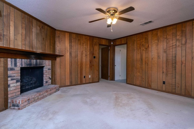 unfurnished living room featuring ceiling fan, light carpet, a textured ceiling, and a brick fireplace