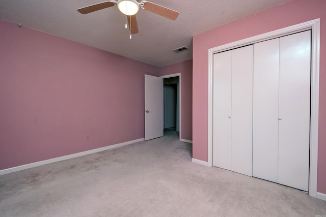 unfurnished bedroom featuring a textured ceiling, ceiling fan, light carpet, and a closet