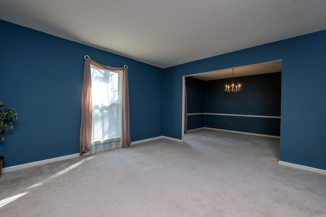 carpeted spare room with a textured ceiling and a notable chandelier